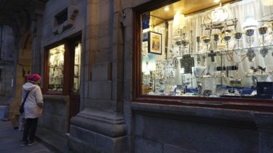 A woman looks at the window of a shop for church devotional items in Santiago de Compostela, making