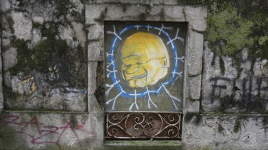 Graffiti of a smiling face on an old wall, pilgrims on Caminho Portugues, Portugal, Spain