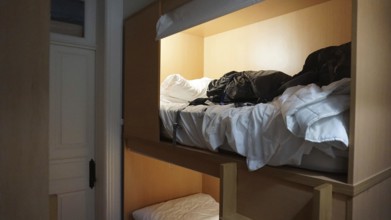 A bunk bed in a hostel room with unmade beds and clothes, Porto, Portugal