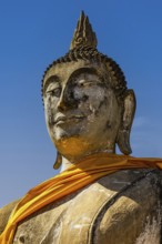 Stone Buddha statue decorated with yellow cloth, historic Buddhist temple complex, Ayutthaya,
