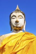 Stone Buddha statue decorated with yellow cloths, historic Buddhist temple complex, Ayutthaya,