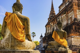 Stone Buddha statues decorated with yellow cloths, historic Buddhist temple complex, Ayutthaya,