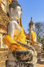 Stone Buddha statues decorated with yellow cloths, historic Buddhist temple complex, Ayutthaya,
