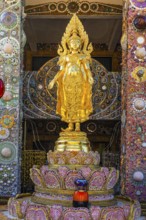 Gilded standing Buddha statue on a base decorated with mosaics and glass works of art, Buddhist