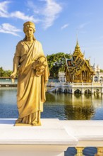 Stone female figure on Dolls Bridge, in the back the open, gilded pavilion, Buddhist temple