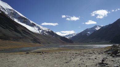 Snowy mountain peaks surround a wide and sparkling clear valley, trekking in Ladakh, Himalayas,