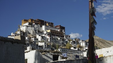 Thiksey mountain monastery with white walls and prayer flags under a cloudless sky, Indus Valley,
