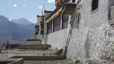 Old secluded Buddhist monastery with white walls against a backdrop of mountains, trekking in