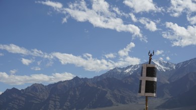Mountain landscape with blue sky and clouds, flag in the foreground, trekking in Ladakh, Himalayas,