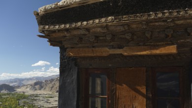 Detail of a wooden roof structure with window and mountain landscape in the background, trekking in