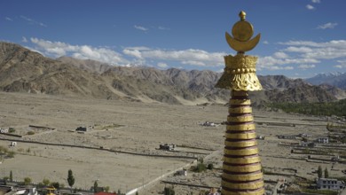 Golden stupa over a vast, mountainous landscape under a glowing sky, trekking in Ladakh, Himalayas,