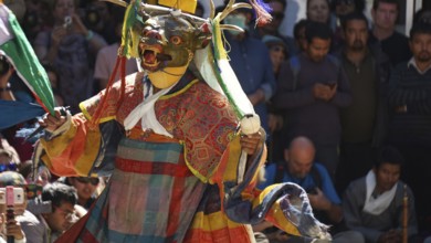 Masked dancer in traditional clothing in front of an audience in Leh, trekking in Ladakh,
