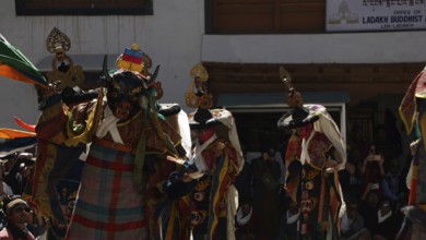 Several masked figures in colorful clothes perform a dance during a festival in Leh, trekking in
