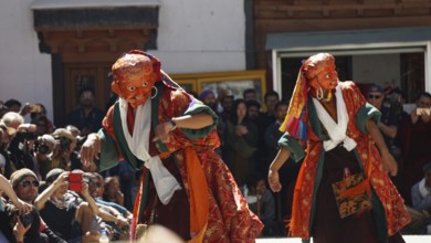 Two dancers in colorful costumes perform a traditional dance in front of an audience, Leh, Trekking