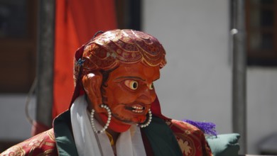 A vivid red-orange masked figure at a Buddhist ritual or dance in Leh, trekking in Ladakh,