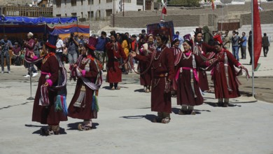 People wearing traditional clothes perform a dance surrounded by spectators at a festival in Leh,