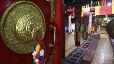 View through the imposing door, magnificent interior of a Buddhist temple with red carpets and