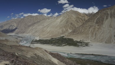 Extensive Nubra Valley with river course and impressive mountains under sunny skies, trekking in