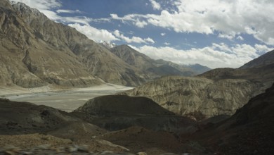 Wide mountain landscape under a cloudy sky with rocky slopes and a valley, trekking in Ladakh,