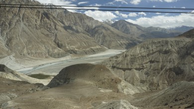 Wide view of a river valley on the way to the Nubra Valley, surrounded by lofty mountain formations