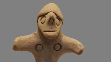 Anthropomorphic votive statuette, delicate clay sculpture with simple facial features on a light