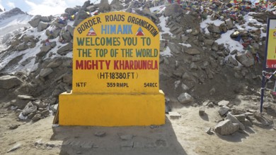 Welcome sign at Khardungla Pass surrounded by rocks and snow, trekking in Ladakh, Himalayas, India