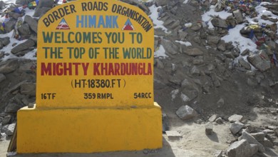 Colourful welcome sign at Khardungla Pass on rocky ground, trekking in Ladakh, Himalayas, India