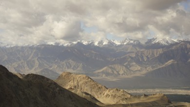 Wide panorama with mountains and snowy peaks under cloudy sky, trekking in Ladakh, Himalayas, India