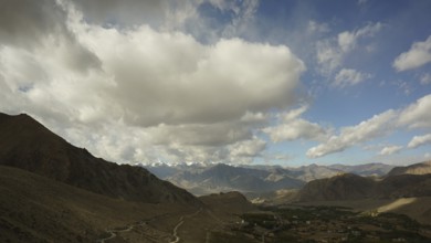 Mountain landscape under a dramatic, cloudy sky with sunny stretches, trekking in Ladakh,