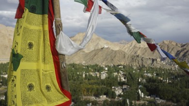 Close-up, colorful prayer flags fluttering in the wind against a mountainous landscape with clear