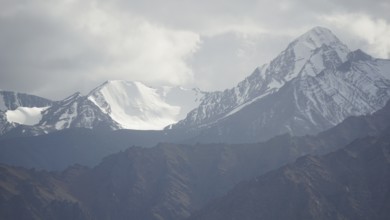 Snowy mountain peaks rise majestically under a cloudy sky, trekking in Ladakh, Himalayas, India