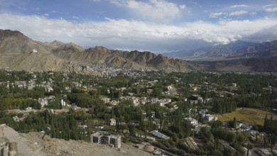 View from above of a city surrounded by mountains under a wide sky, trekking in Ladakh, Himalayas,