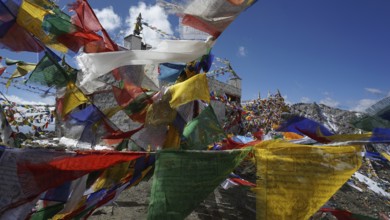 Close-up, colorful prayer flags waving in the wind in front of a temple at Khardung-La Pass in the