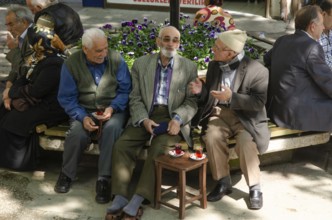 Bursa, Turkey. April 21st 2014 Old Turkish men chatting and drinking tea in a tree shaded square,