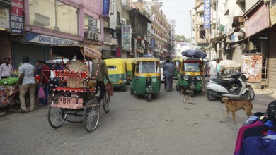 Busy shopping street with rickshaws and people in the bustling Indian city of Delhi, India