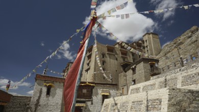 Traditional monastery with colorful prayer flags under blue sky, Ladakh, North India, Himalayas,
