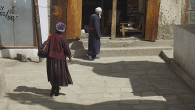 People in traditional clothing walking along a stone road, Leh, Ladakh, North India, Himalayas,