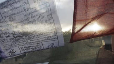 Prayer flags waving in the wind with texts and translucent sun in the background, Leh, Ladakh,