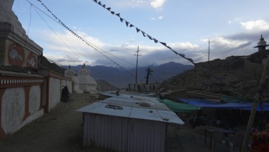Monastery structures under a blue sky decorated with prayer flags, outskirts of Leh, Ladakh,