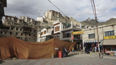 Leh Palace and historic buildings with market stalls and tents against a mountainous backdrop in