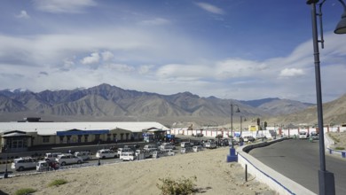 Taxis wait in Leh at the airport in front of surrounding mountains under a clear sky, Leh, Ladakh,