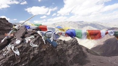 Colourful prayer flags flying over a rocky mountain landscape, trekking at Stok La Pass in Ladakh,