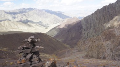 Stone tower as a guide with a view of extensive, rocky mountain landscape, trekking at Stok La Pass