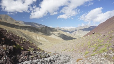 Rocky mountain landscape with blue sky and scattered vegetation, trekking at Stok La Pass in