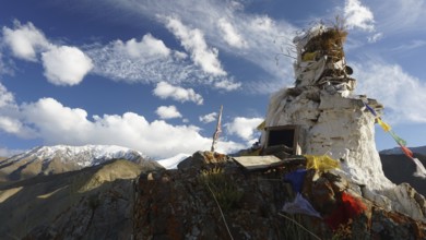 A white Buddhist site on a mountain top, trekking to Stok la Pass with clear blue sky backdrop,