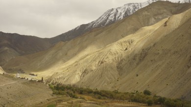 Wide valley with dramatic, barren mountain landscapes under cloudy sky, trekking in Ladakh,