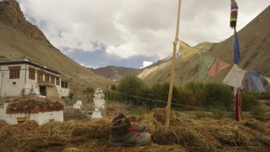 Mountain boot, hiking boots next to prayer flags against mountainous landscape with turbulent