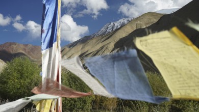 Prayer flags waving in the wind against a majestic mountain backdrop with clear skies, trekking in