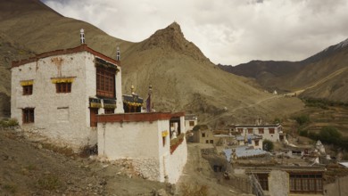 Traditional village on a mountainside under dramatic sky in the Himalayas, trekking in Ladakh,
