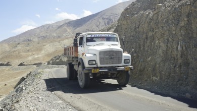 A sturdy truck on a narrow mountain road on a barren mountain landscape, Ladakh, Himalayas, India